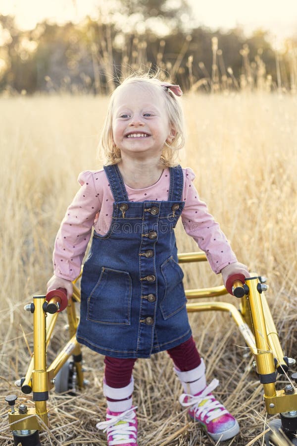 Photo d'une petite fille handicapée mignonne marchant avec un marcheur spécial image stock