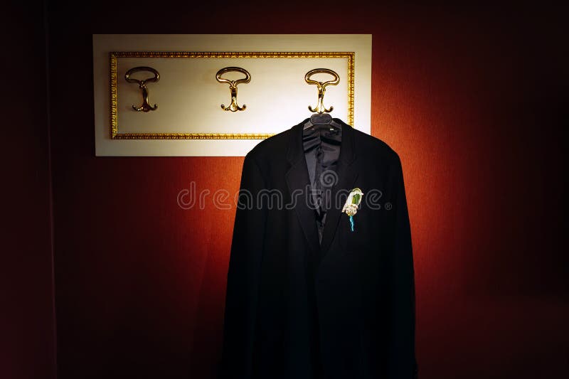 Vintage photo: black wedding suit hanging on a hanger. Boutonniere of flowers on the jacket of the groom. Vintage photo: black wedding suit hanging on a hanger. Boutonniere of flowers on the jacket of the groom.