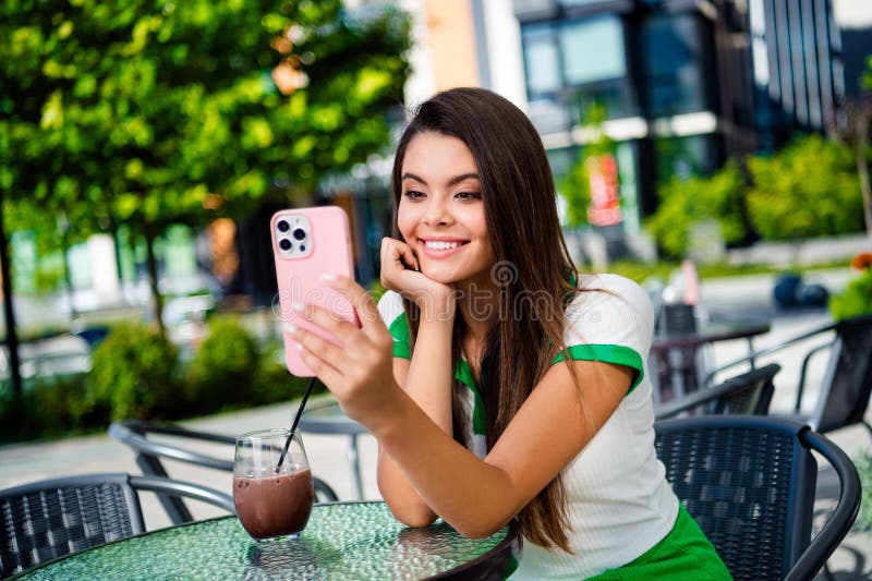 Photo of cheerful lovely girl enjoying break pause relax rest in cafe park talking with friends online spring day outside. Photo of cheerful lovely girl enjoying break pause relax rest in cafe park talking with friends online spring day outside.