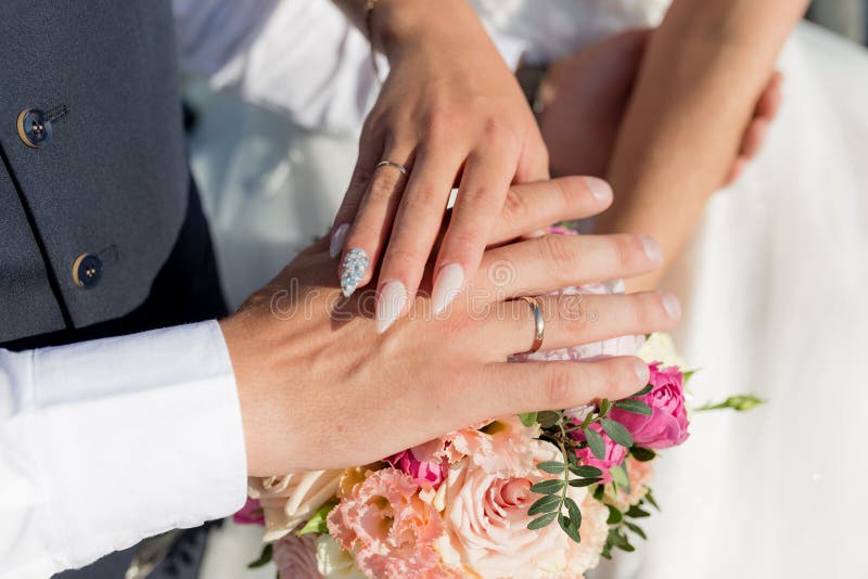 Photo de l'homme et de la femme avec alliance Un jeune couple marié se tenant la main, jour de la cérémonie de mariage Les mains photographie stock Photo de l'homme et de la femme avec alliance Un jeune couple marié se tenant la main, jour de la cérémonie de mariage Les mains photographie stock