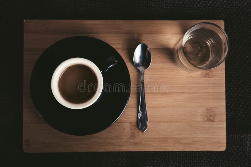 Photo de petite tasse de café noir lumineuse sur la table en bois avec la cuillère et le verre de thé pleins de l'eau claire sur photo libre de droits Photo de petite tasse de café noir lumineuse sur la table en bois avec la cuillère et le verre de thé pleins de l'eau claire sur photo libre de droits