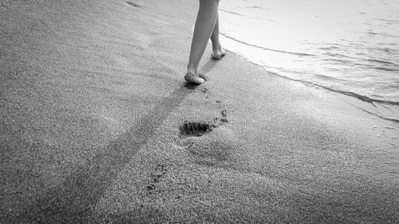 Photo de plan rapproché de la belle jeune femme aux pieds nus marchant dans les vagues chaudes calmes de mer contre le coucher du image libre de droits Photo de plan rapproché de la belle jeune femme aux pieds nus marchant dans les vagues chaudes calmes de mer contre le coucher du image libre de droits