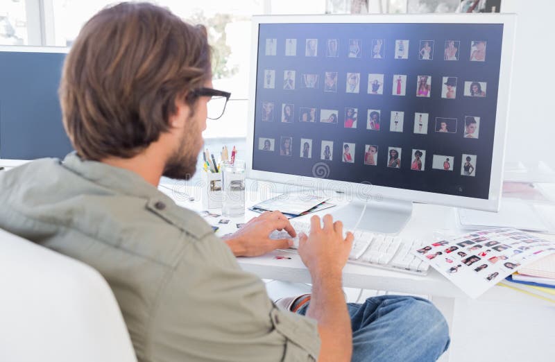 Photo editor looking at thumbnails on computer at his desk. Computer editing stock images, royalty-free photos and pictures