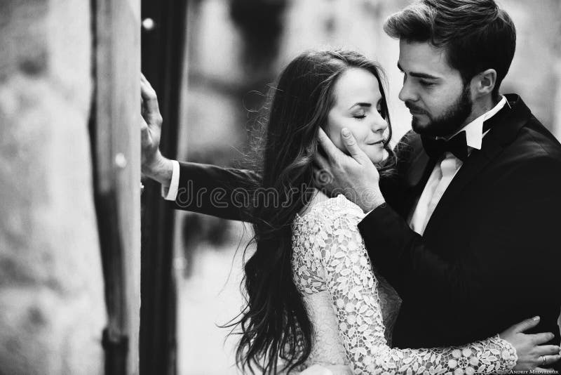 Photo en noir et blanc. Épouser les couples étreignant dans la vieille ville. Mariée élégante dans la robe longs et marié blancs d photographie stock libre de droits