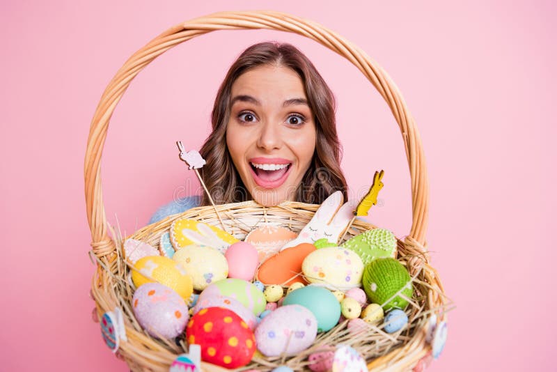 Cute little child wearing a fun hairstyle on Easter Day Girl with basket  of shiny eggs looks at an easter egg squinting Stock Photo  Alamy