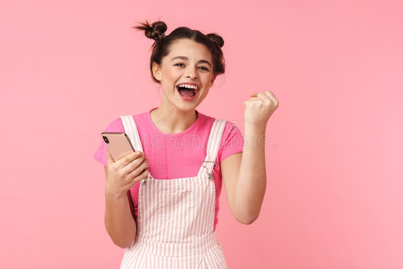 Photo of excited nice girl holding cellphone and making winner gesture