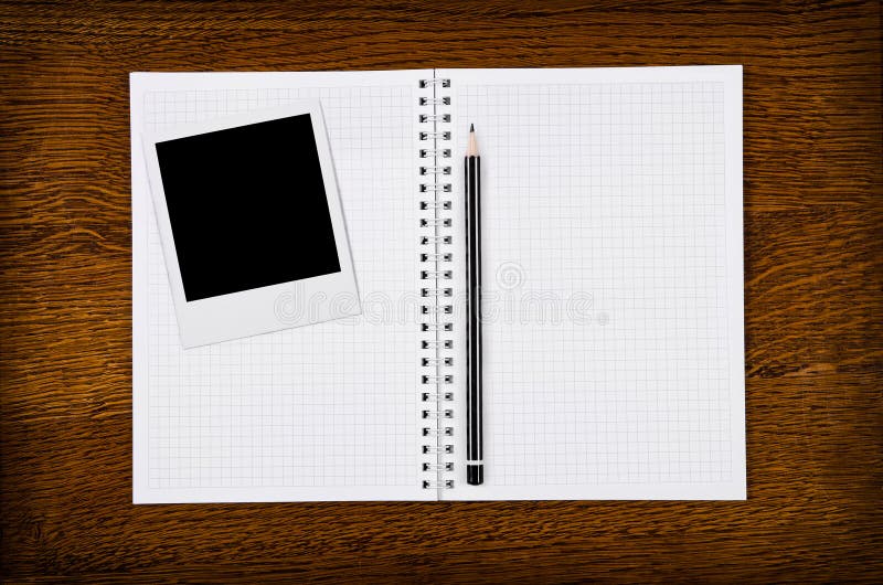 Photo frame on blank notebook with pencil