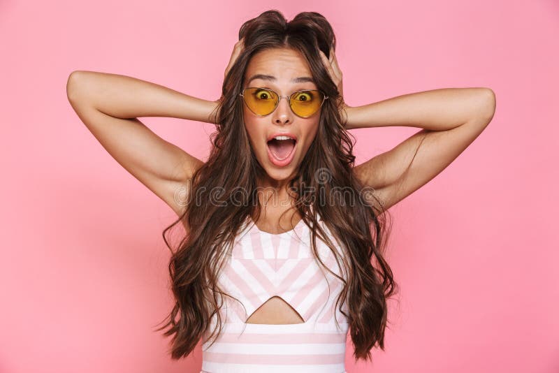 Photo of gorgeous woman 20s wearing sunglasses rejoicing with surprise and screaming, isolated over pink background stock image Photo of gorgeous woman 20s wearing sunglasses rejoicing with surprise and screaming, isolated over pink background stock image