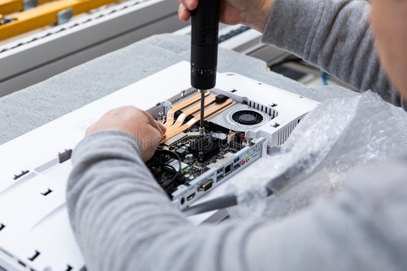 Photo of hand of a man who assembles a computer monitor system block on an conveyor belt at a monoblock assembly plant. Modern high-tech factory.