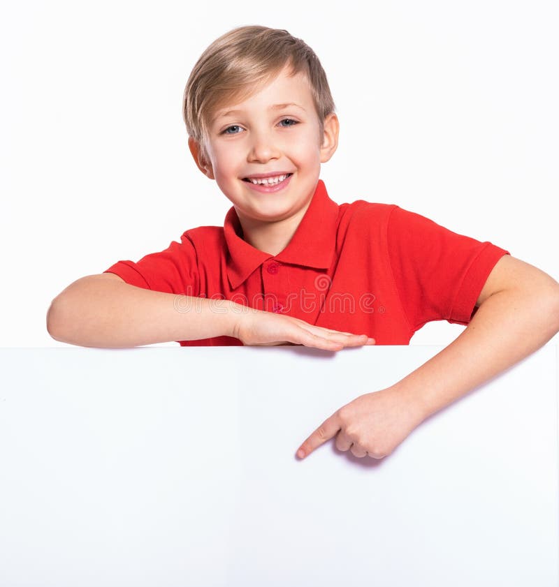 Photo of  a happy smiling kid look outs from the blank billboard.  Portrait of  cheerful child pointing on white banner.  Portrait