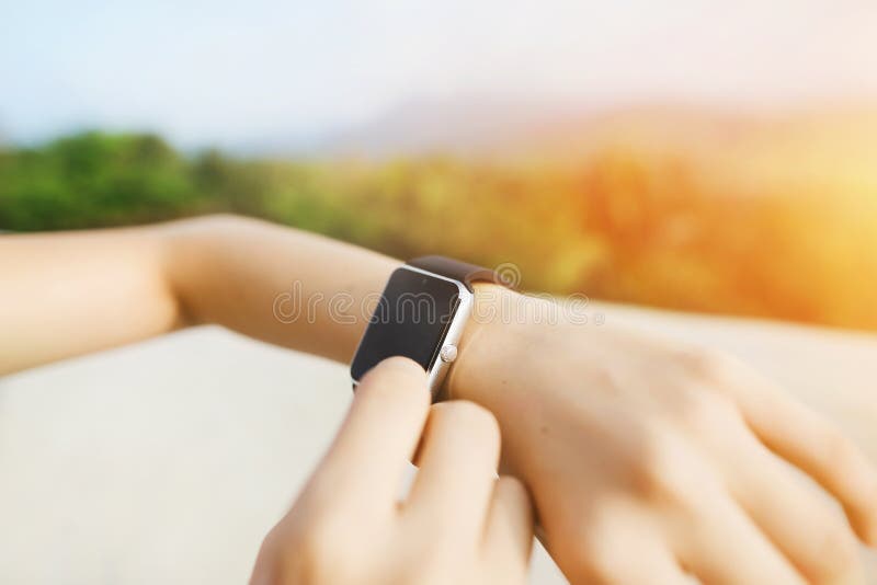 Photo légère des mains de plan rapproché utilisant le smartwatch avec des montagnes à l'arrière-plan photo libre de droits Photo légère des mains de plan rapproché utilisant le smartwatch avec des montagnes à l'arrière-plan photo libre de droits
