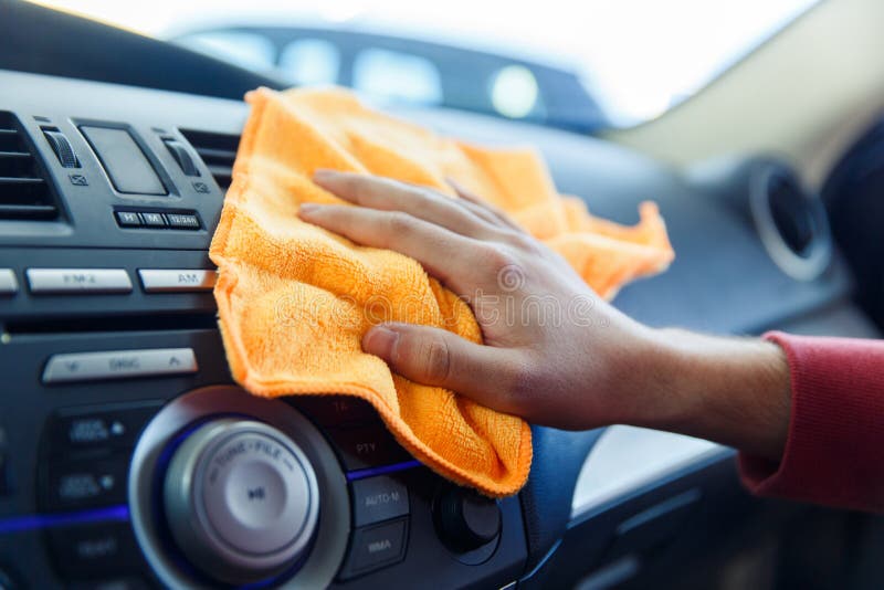 Photo of male`s hand with orange rag washing car interior, close-up