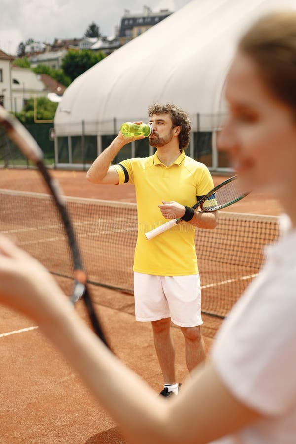 Male Tennis Player Standing In Court And Woman Standing In Front Stock