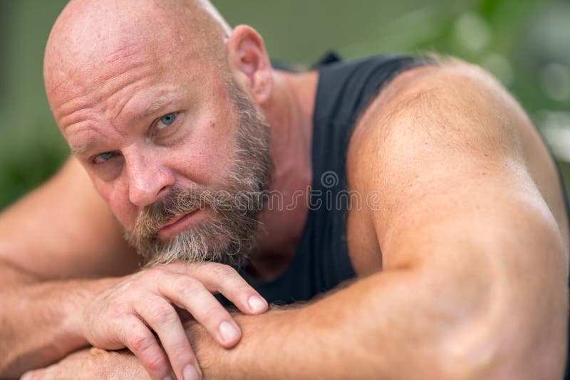 Photo of a man laying his head on arms looking into camera