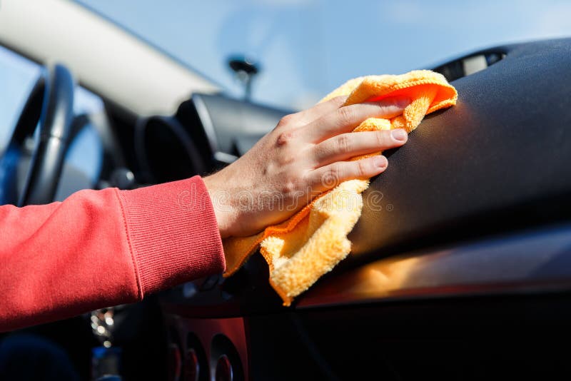 Photo of man`s hand with orange rag washing car interior, close-up