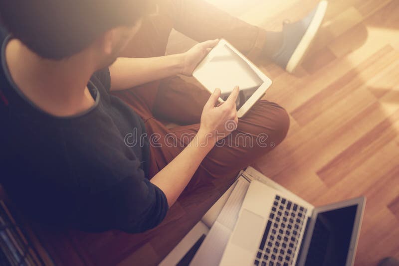 Photo of man touching screen Of generic design tablet holding in his hands. Laptop on the floor. stock images Photo of man touching screen Of generic design tablet holding in his hands. Laptop on the floor. stock images