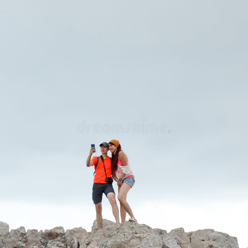 Photo of man and woman taking pictures of themselves while standing on mountain stock photo Photo of man and woman taking pictures of themselves while standing on mountain stock photo