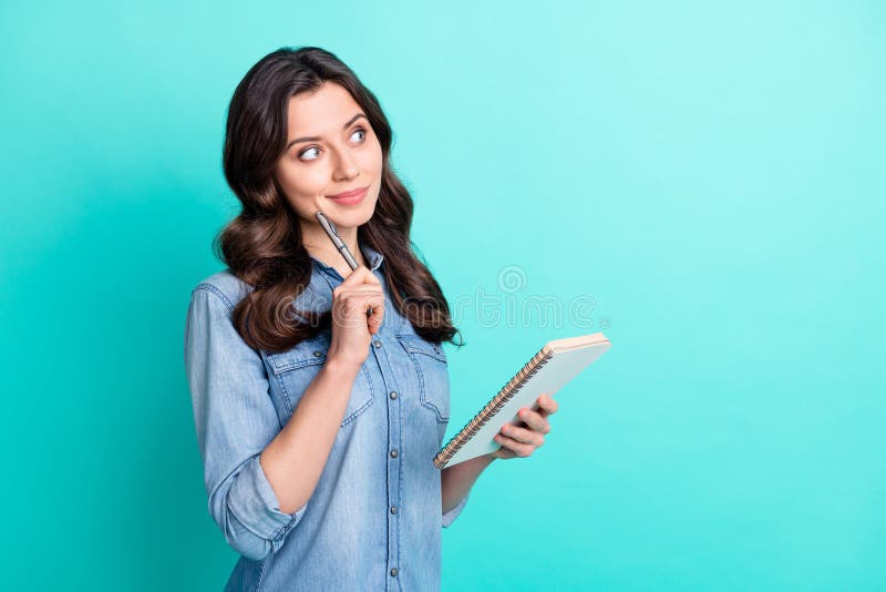 Photo of minded happy young woman look empty space hold notebook good mood isolated on teal color background