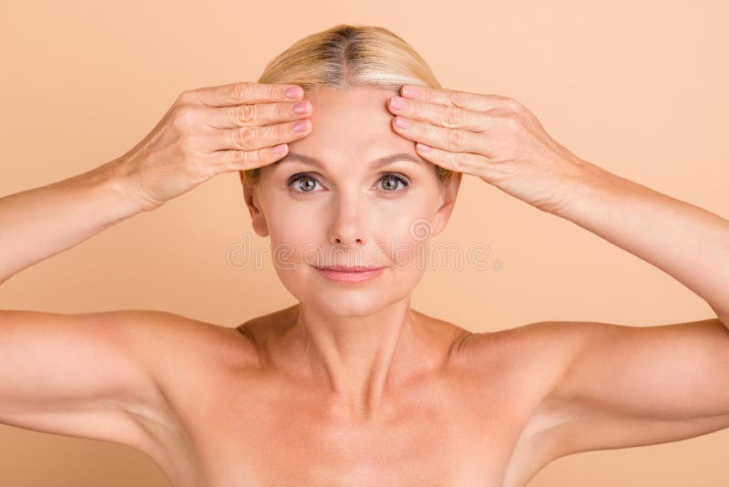 Photo of natural beauty aged lady naked shoulders touch forehead perfect skin look mirror anti age cream uplift action