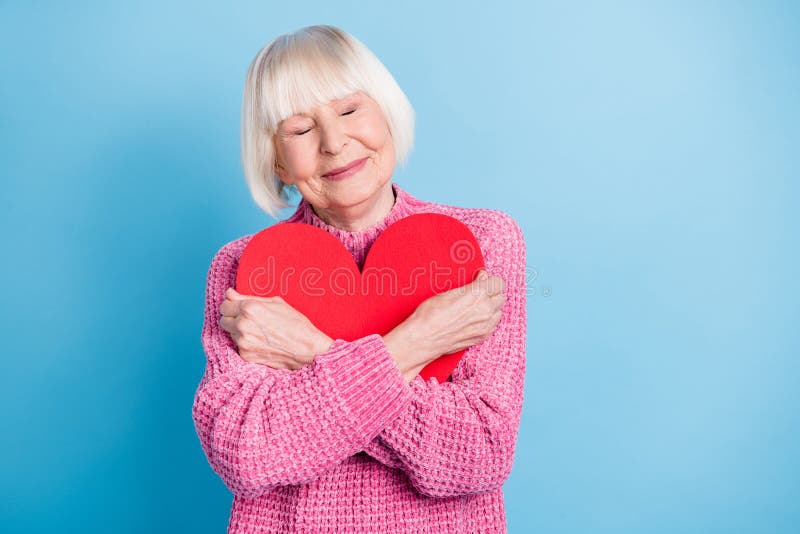 Photo portrait of calm old woman hugging red heart card isolated on pastel blue colored background. Myself concept stock images, royalty-free photos and pictures