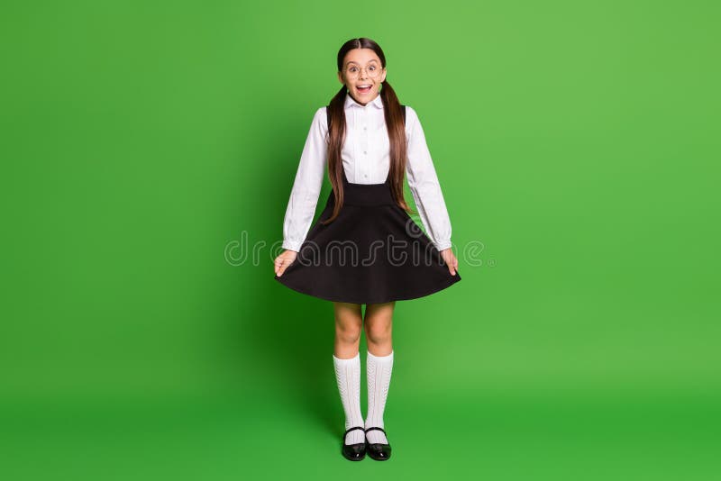 Photo portrait of shocked girl showing her school uniform isolated on vivid green colored background