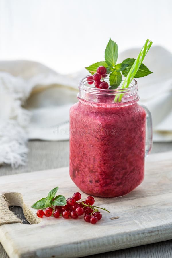 Photo of red currant smoothie in jar with straw on light background. Fresh organic Smoothie. Health or detox diet food