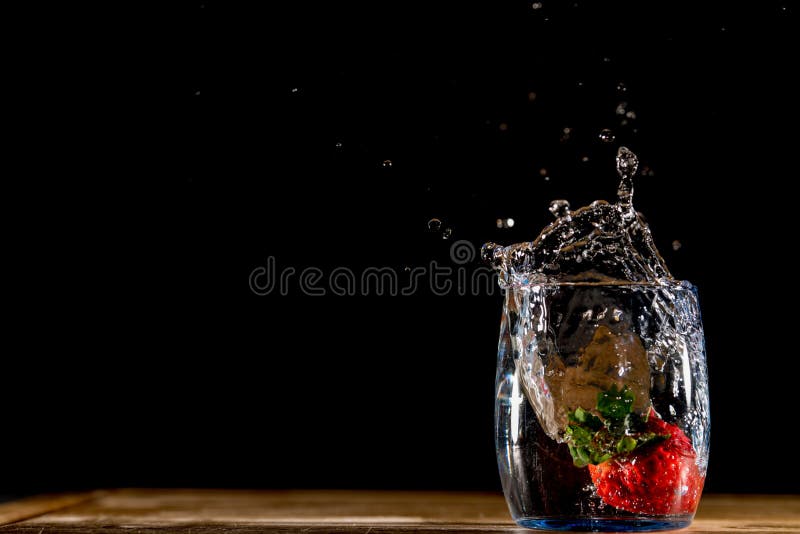 Photo of a red strawberry falling into a glass of water and making a splash royalty free stock photography Photo of a red strawberry falling into a glass of water and making a splash royalty free stock photography