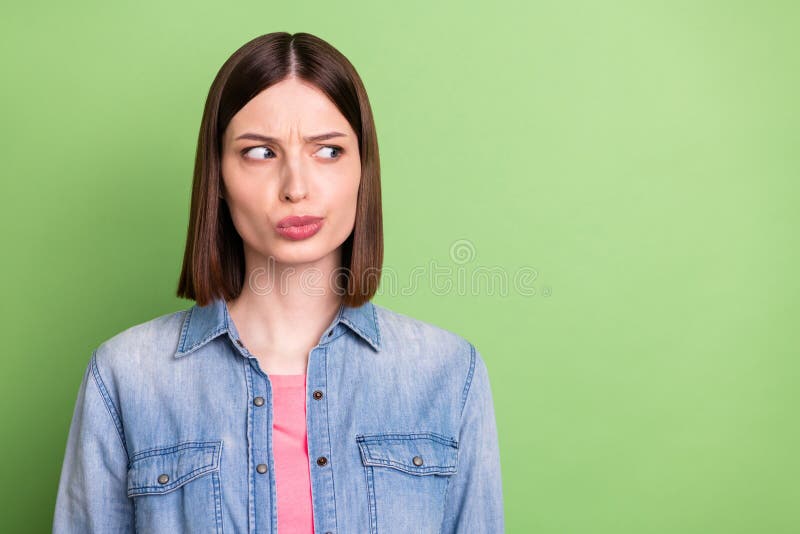 Photo of sad brunette hair young lady look empty space wear jeans jacket isolated on green color background