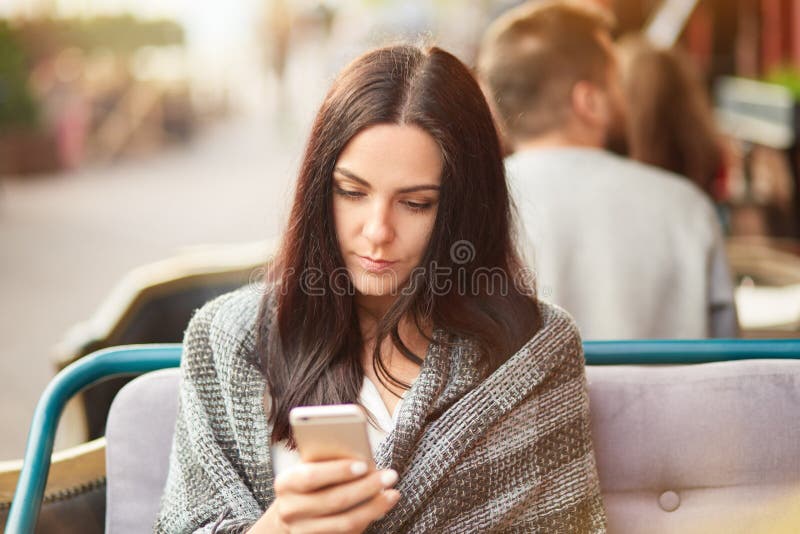 Photo of Serious Brunette Young Lady Uses New Cell Phone for Chatting and Communication, Waits for Order in Outside Cafeteria, Stock Photo - Image of messaging, device: 135508346 Photo of Serious Brunette Young Lady Uses New Cell Phone for Chatting and Communication, Waits for Order in Outside Cafeteria, Stock Photo - Image of messaging, device: 135508346