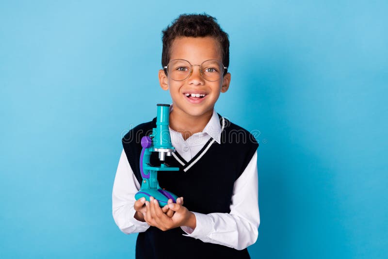Photo of smart positive boy toothy smile hands hold telescope on blue color background stock photo