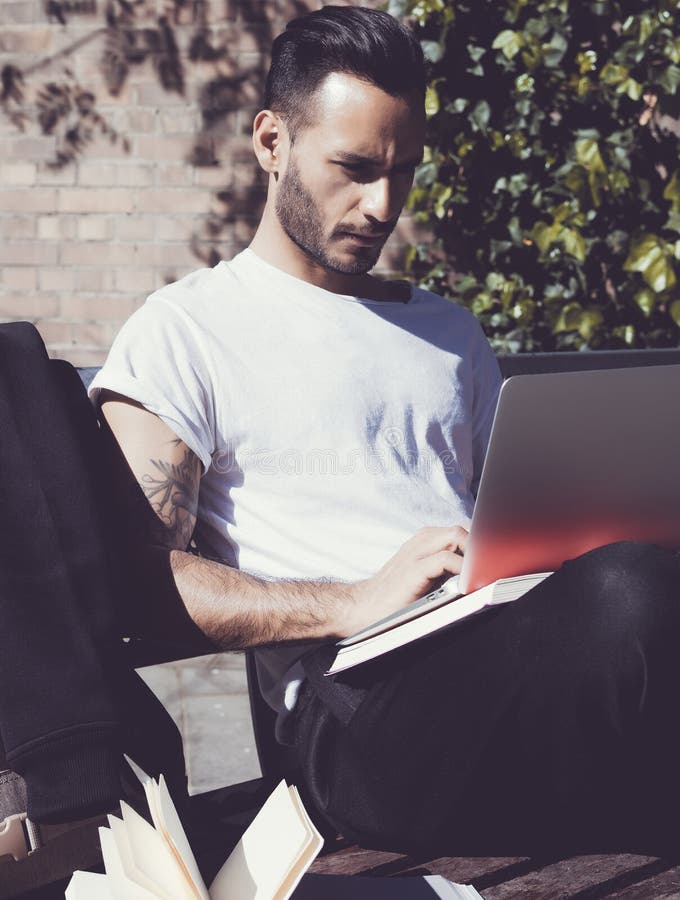 Photo student sitting city park bench and texting message notebook. Using wireless internet.Studying at the University stock image Photo student sitting city park bench and texting message notebook. Using wireless internet.Studying at the University stock image