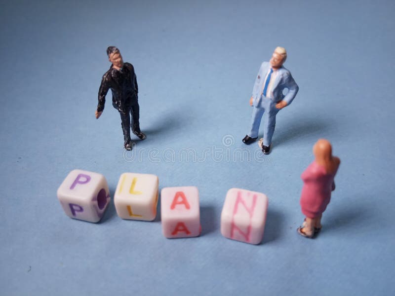 Top View Close Up Conceptual / Illustration 2 Miniature Figure Businessman and 1 Businesswoman Discussing to make a Business Plan