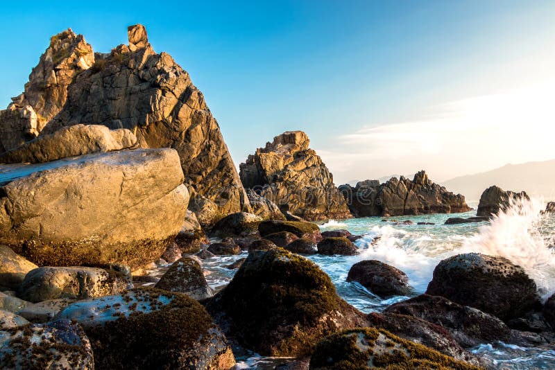 Nature Seascape with Rough Boulders, Pristine Beach and Surging Waves in Morning Sunshine royalty free stock photos Nature Seascape with Rough Boulders, Pristine Beach and Surging Waves in Morning Sunshine royalty free stock photos