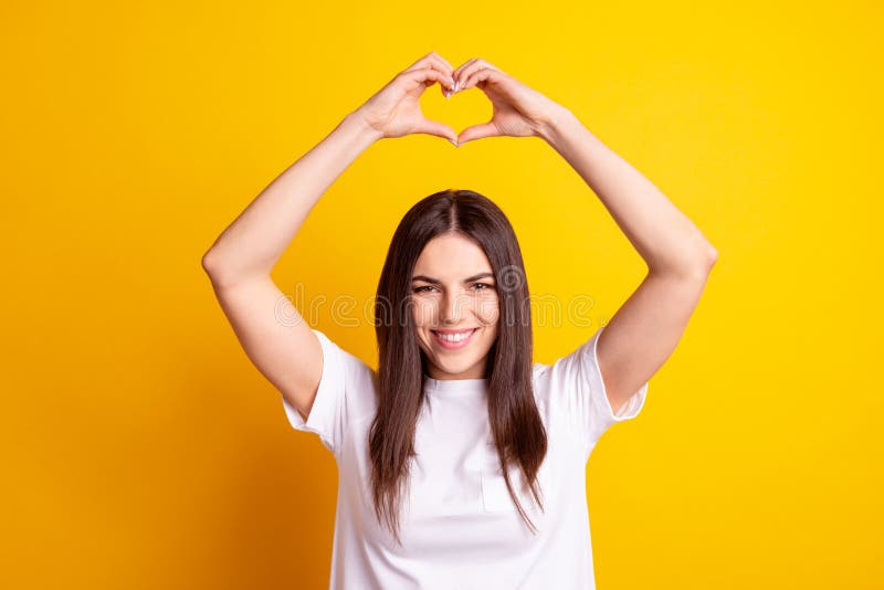 Photo of young attractive girl show fingers heart symbol feelings love romance isolated over yellow color background stock image