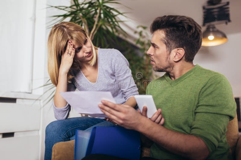 Young couple embracing and calculating the bills at home stock photos Young couple embracing and calculating the bills at home stock photos