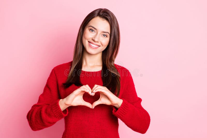 Photo of young cute girl show heart figure beaming shiny smile wear red sweater isolated pink color background