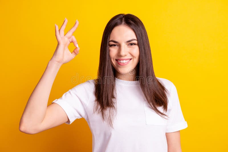 Photo of young girl show fingers okey symbol ads quality recommendation promotion isolated over yellow color background stock photography