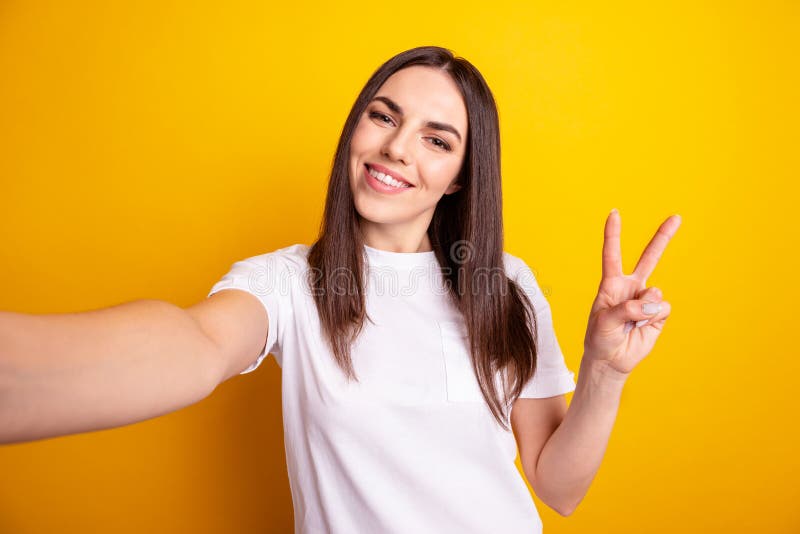 Photo of young pretty girl show fingers peace cool v-symbol sshoot selfie video call isolated over yellow color stock image