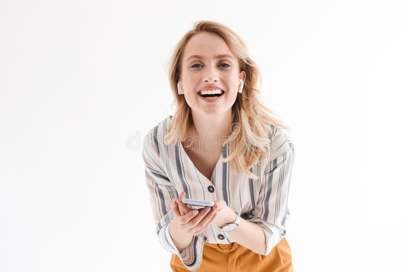 Photo of young smiling woman wearing wrist watch using cellphone and earpods