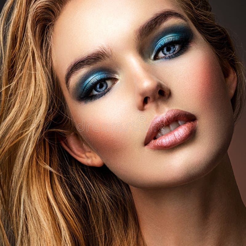 Photo of young woman with style make-up. Portrait of blonde woman with a beautiful face. Closeup face with stylish blue makeup. Fashion model with long hair, studio shot. Fashion concept