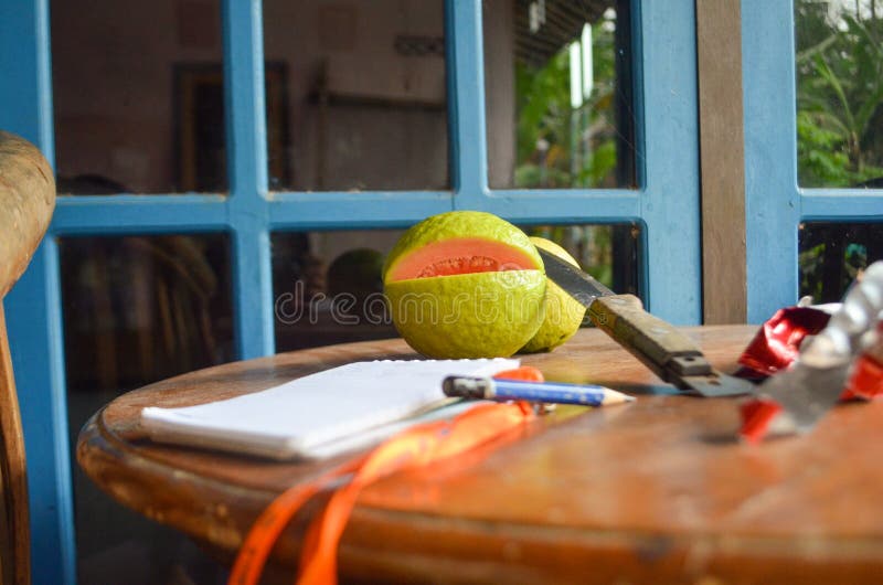 Photograph of several objects such as guava, pencil, knife, notebook on a wooden table royalty free stock photos