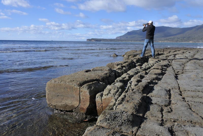 Photographe de voyage photographiant le trottoir en mosaïque en péninsule Tasmanie Australie de Tasman photos stock Photographe de voyage photographiant le trottoir en mosaïque en péninsule Tasmanie Australie de Tasman photos stock