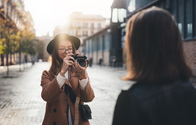 Photographer with camera take photo model girlfriend in europe city. Blogger photoshoot concept. Tourist smiling girl travels