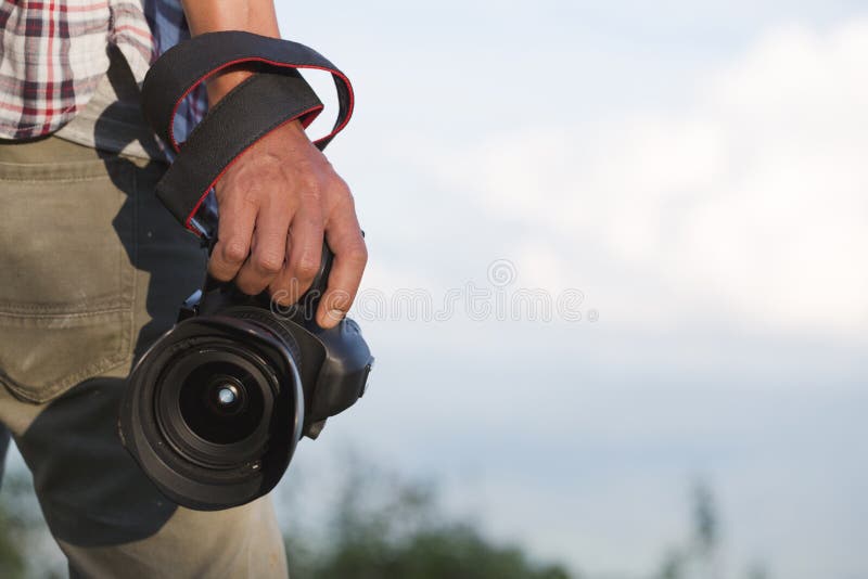 Photographer holding his camera. Travelers hold a DSLR camera on stock image Photographer holding his camera. Travelers hold a DSLR camera on stock image