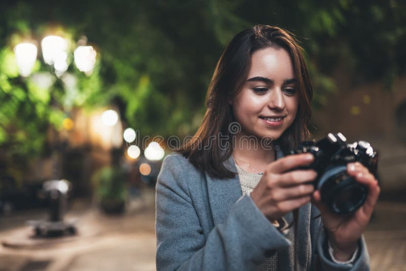 Photographer tourist girl using retro camera on background bokeh light in evening city, Blogger photoshoot hobby