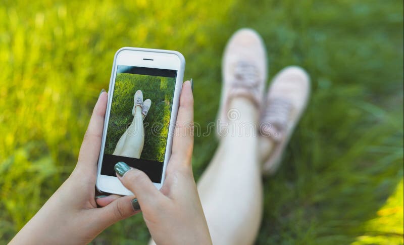 Photographes себя девушки и ее ноги в тапках на телефоне стоковое изображение rf Photographes себя девушки и ее ноги в тапках на телефоне стоковое изображение rf