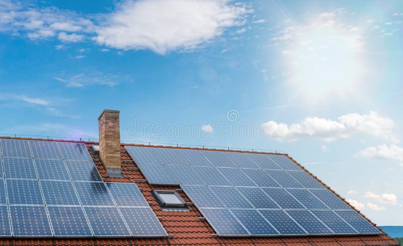 Photovoltaic or solar panels on roof against blue sky