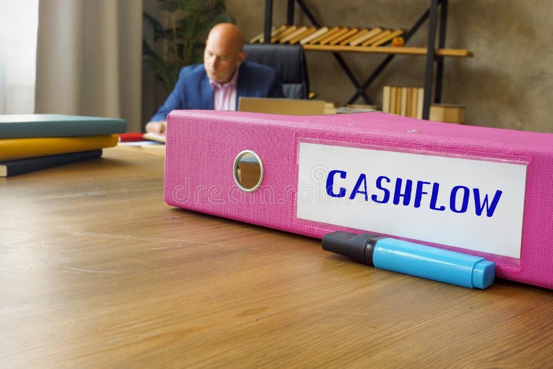 Phrase CASHFLOW on the folder for documents. Businessman working at work table royalty free stock photos
