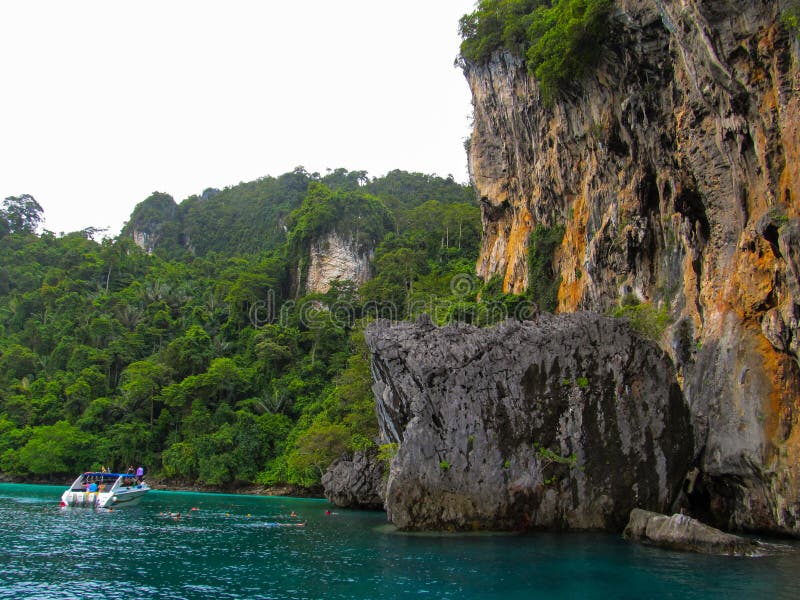 Phuket Phuket Thailand - 10 15 2012: det lilla fartyget med turister som stoppas nära ett enormt, vaggar, så att turister kunde f arkivbild Phuket Phuket Thailand - 10 15 2012: det lilla fartyget med turister som stoppas nära ett enormt, vaggar, så att turister kunde f arkivbild
