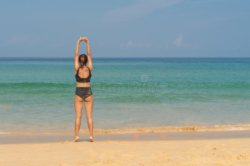Phuket, Thailand - March 30, 2019: Slender girl in a black bathing suit with a tattoo on his shoulder doing yoga royalty free stock images Phuket, Thailand - March 30, 2019: Slender girl in a black bathing suit with a tattoo on his shoulder doing yoga royalty free stock images